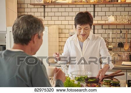 Stock Image - Japanese senior couple in the kitchen. Fotosearch