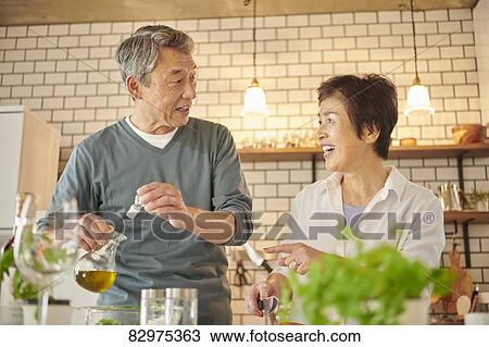 Stock Image - Japanese senior couple in the kitchen. Fotosearch