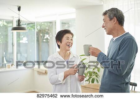 Stock Image - Japanese senior couple in the living room. Fotosearch