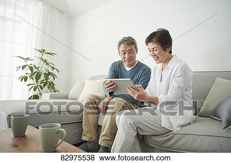 Stock Photo - Japanese senior couple on the sofa. Fotosearch
