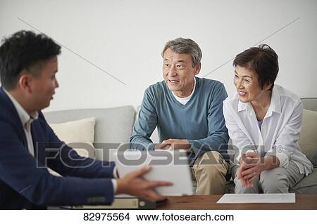 Picture - Japanese senior couple talking with consultant. Fotosearch