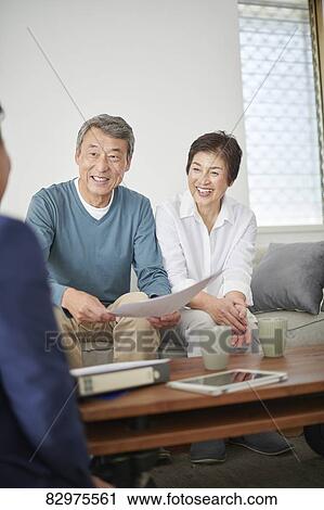 Stock Image - Japanese senior couple talking with consultant. Fotosearch