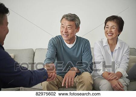 Stock Image - Japanese senior couple talking with consultant. Fotosearch