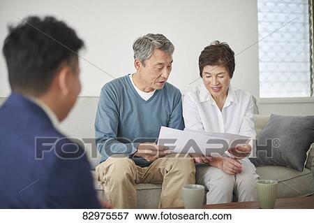 Stock Photo - Japanese senior couple talking with consultant. Fotosearch