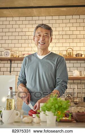 Stock Image - Japanese senior man in the kitchen. Fotosearch