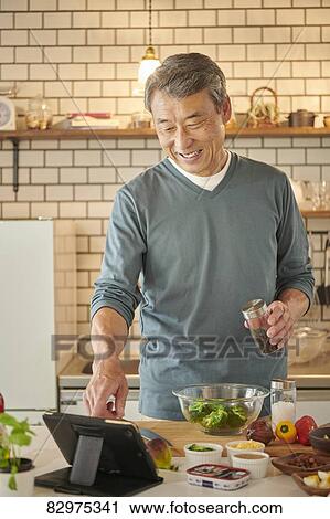 Stock Image - Japanese senior man in the kitchen. Fotosearch