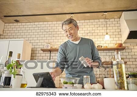 Stock Image - Japanese senior man in the kitchen. Fotosearch