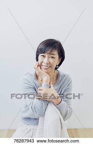 Stock Image - Japanese senior woman against white wall. Fotosearch