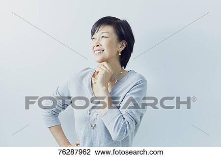 Stock Image - Japanese senior woman against white wall. Fotosearch