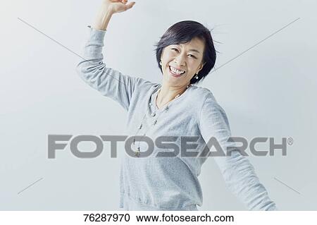 Stock Image - Japanese senior woman against white wall. Fotosearch
