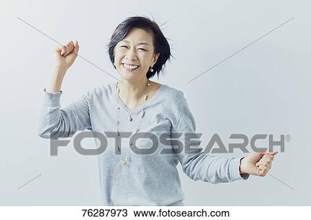 Stock Image - Japanese senior woman against white wall. Fotosearch