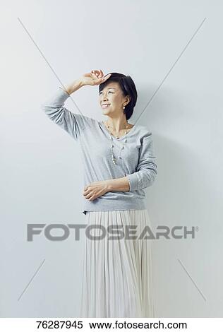 Stock Photography - Japanese senior woman against white wall. Fotosearch