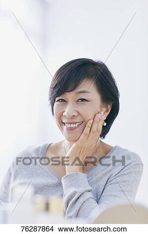 Picture - Japanese senior woman doing skin care. Fotosearch