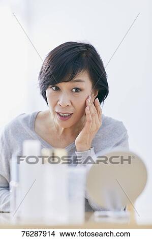 Picture - Japanese senior woman doing skin care. Fotosearch