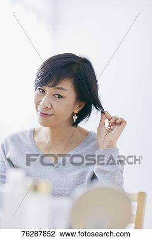 Stock Image - Japanese senior woman doing skin care. Fotosearch