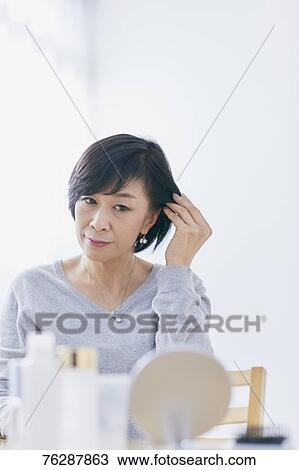 Stock Image - Japanese senior woman doing skin care. Fotosearch
