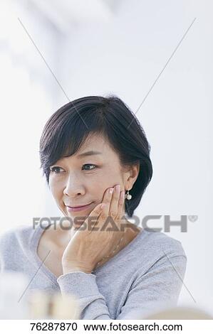 Stock Image - Japanese senior woman doing skin care. Fotosearch
