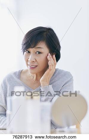 Stock Image - Japanese senior woman doing skin care. Fotosearch