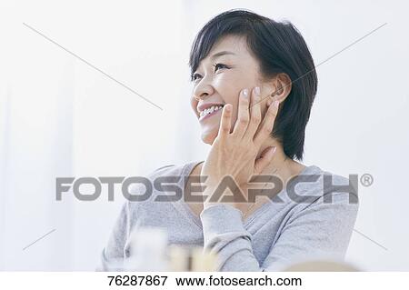 Stock Photo - Japanese senior woman doing skin care. Fotosearch