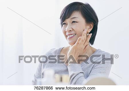 Stock Photograph - Japanese senior woman doing skin care. Fotosearch