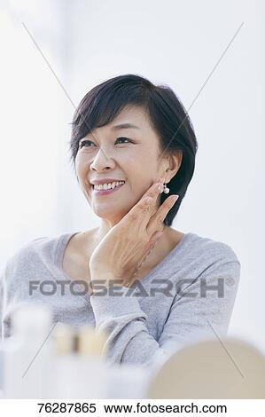 Stock Photography - Japanese senior woman doing skin care. Fotosearch