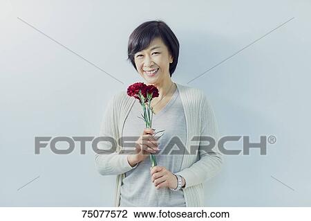 Japanese senior woman holding flowers View Large Photo Image Stock Image - Japanese senior woman holding flowers. Fotosearch