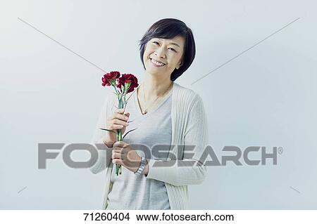 Japanese senior woman holding red roses View Large Photo Image Picture - Japanese senior woman holding red roses. Fotosearch