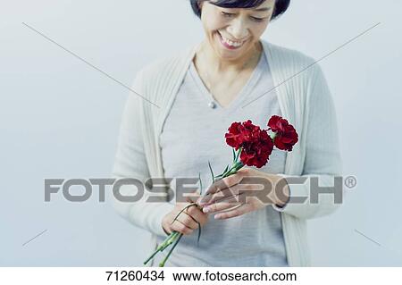 Picture - Japanese senior woman holding red roses. Fotosearch