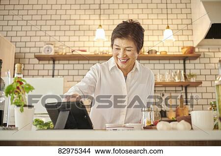 Picture - Japanese senior woman in the kitchen. Fotosearch