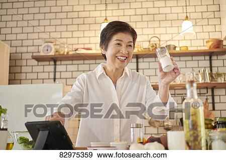 Stock Photo - Japanese senior woman in the kitchen. Fotosearch