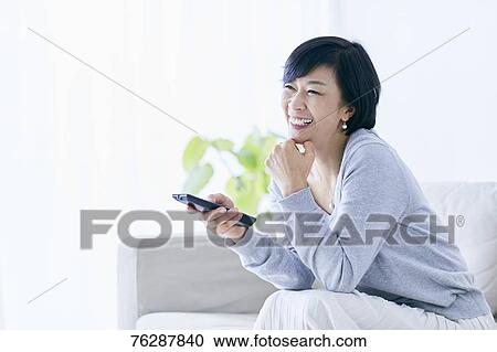 Stock Image - Japanese senior woman on sofa. Fotosearch