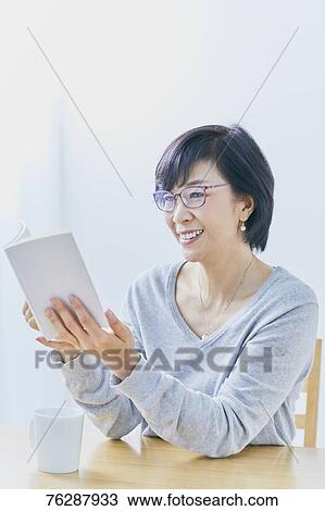 Japanese senior woman reading book at table View Large Photo Image Stock Image - Japanese senior woman reading book at table. Fotosearch