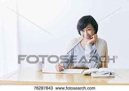 Stock Image - Japanese senior woman working at table. Fotosearch