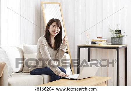 Picture - Japanese woman buying online. Fotosearch