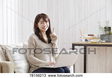 Stock Image - Japanese woman buying online. Fotosearch