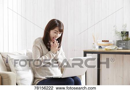 Stock Image - Japanese woman buying online. Fotosearch