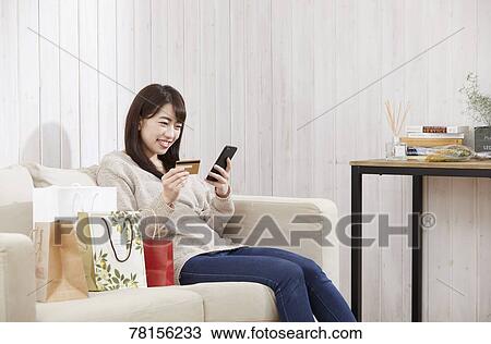 Stock Image - Japanese woman buying online. Fotosearch