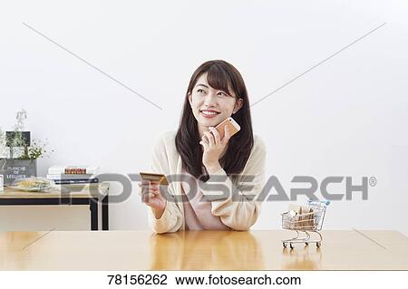 Stock Image - Japanese woman buying online. Fotosearch