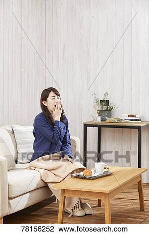 Stock Image - Japanese woman eating in a pajamas. Fotosearch