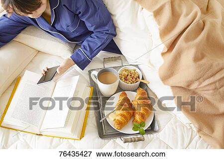 Stock Photo - Japanese woman having breakfast in bed. Fotosearch