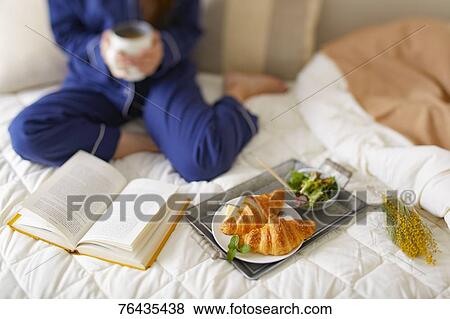 Stock Photo - Japanese woman having breakfast in bed. Fotosearch