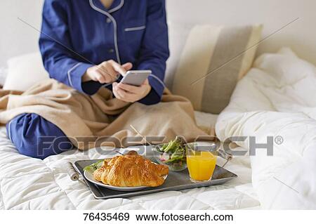 Stock Photo - Japanese woman having breakfast in bed. Fotosearch