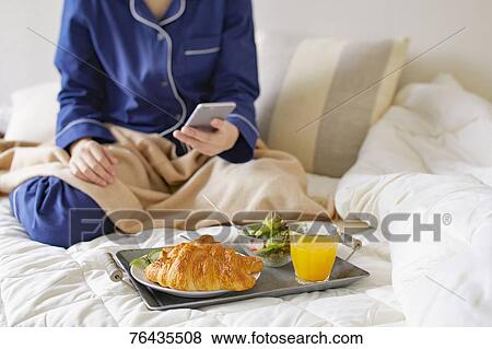 Stock Photo - Japanese woman having breakfast in bed. Fotosearch