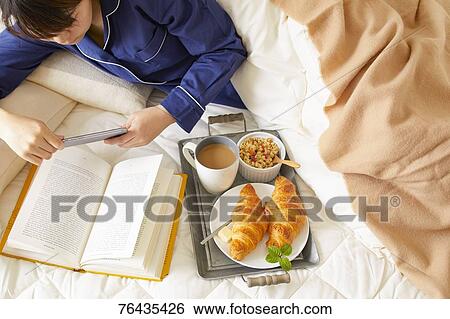 Stock Photograph - Japanese woman having breakfast in bed. Fotosearch