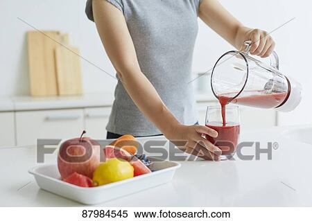 Stock Photography - Japanese woman making smoothie in the kitchen. Fotosearch