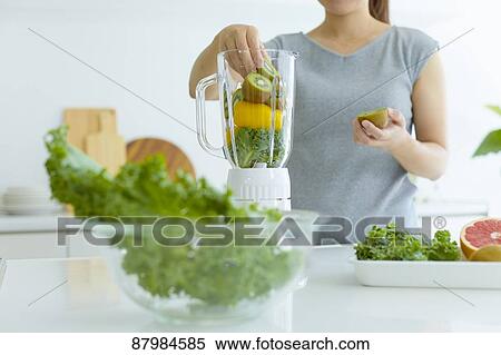 Stock Photography - Japanese woman making smoothie in the kitchen. Fotosearch