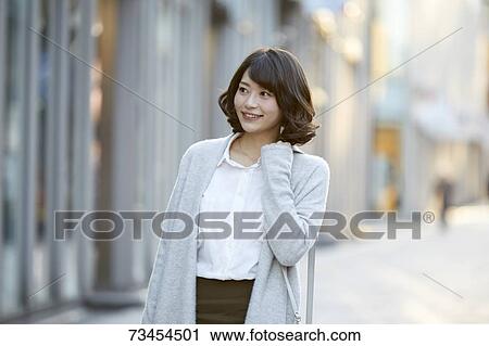 Stock Image - Japanese woman window shopping downtown Tokyo. Fotosearch