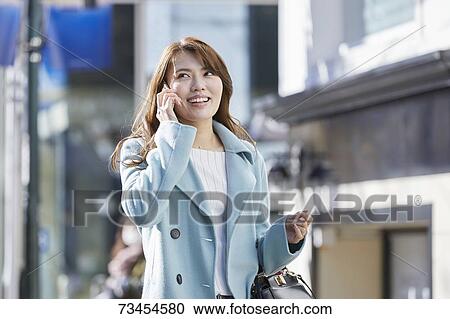 Stock Image - Japanese woman window shopping downtown Tokyo. Fotosearch