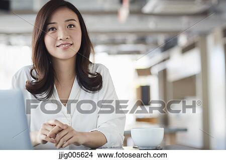Picture - Japanese woman with laptop in a stylish cafe. Fotosearch