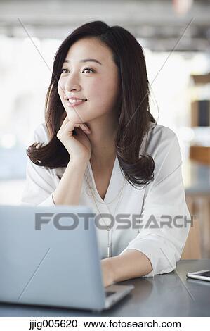 Stock Image - Japanese woman with laptop in a stylish cafe. Fotosearch